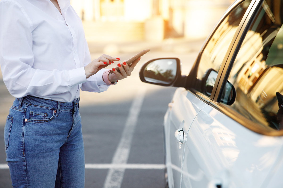 woman-dialing-phone-next-to-car
